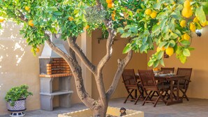 An outdoor patio with a dining table, chairs, a barbecue grill, and a tree with lemons. - JUNIPER (INCA) - Cozy town house with above ground pool in the center of Mallorca. Free WI (Inca)