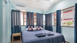 Ein Schlafzimmer mit Bett, Kissen, einem kleinen Tisch und Vorhängen.