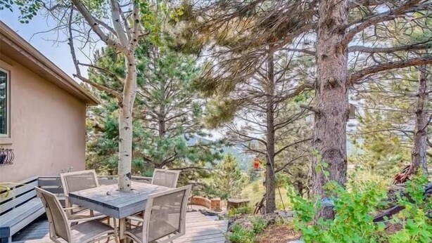 An outdoor patio with a wooden deck, metal chairs, and a table. - Mountain Retreat Near Red Rocks -Private Deck -Mountain Views - Hike, Bike, Ski (Golden)