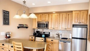 A kitchen with wooden cabinets, a stainless steel refrigerator, a microwave, and a stove. - Mountain Retreat Near Red Rocks -Private Deck -Mountain Views - Hike, Bike, Ski (Golden)