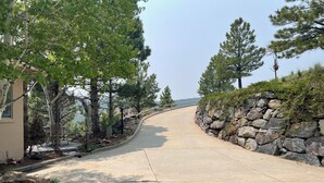 A curved driveway leading to a house with a stone wall on one side and trees on the other. - Mountain Retreat Near Red Rocks -Private Deck -Mountain Views - Hike, Bike, Ski (Golden)