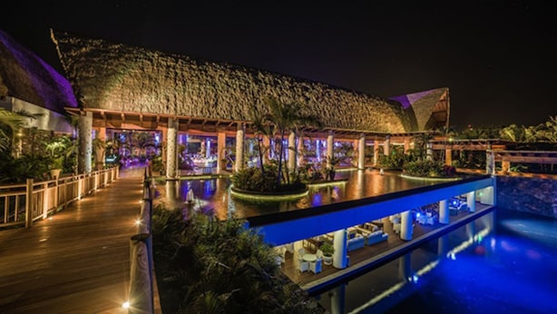 Un complexe hôtelier doté d’une piscine, d’un espace extérieur aménagé et d’une structure à toit de chaume.