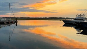 Una marina tranquila con barcos amarrados, reflejando el cielo al atardecer.