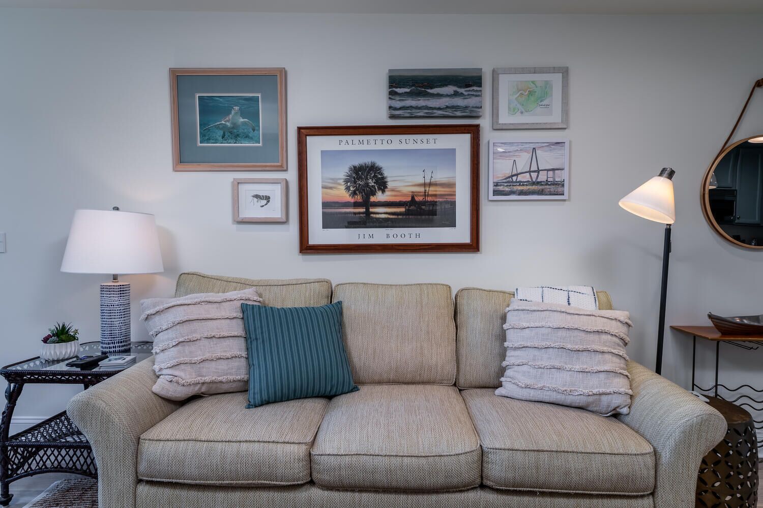 A living room with a sofa, framed artwork, a lamp, and a side table with a plant.