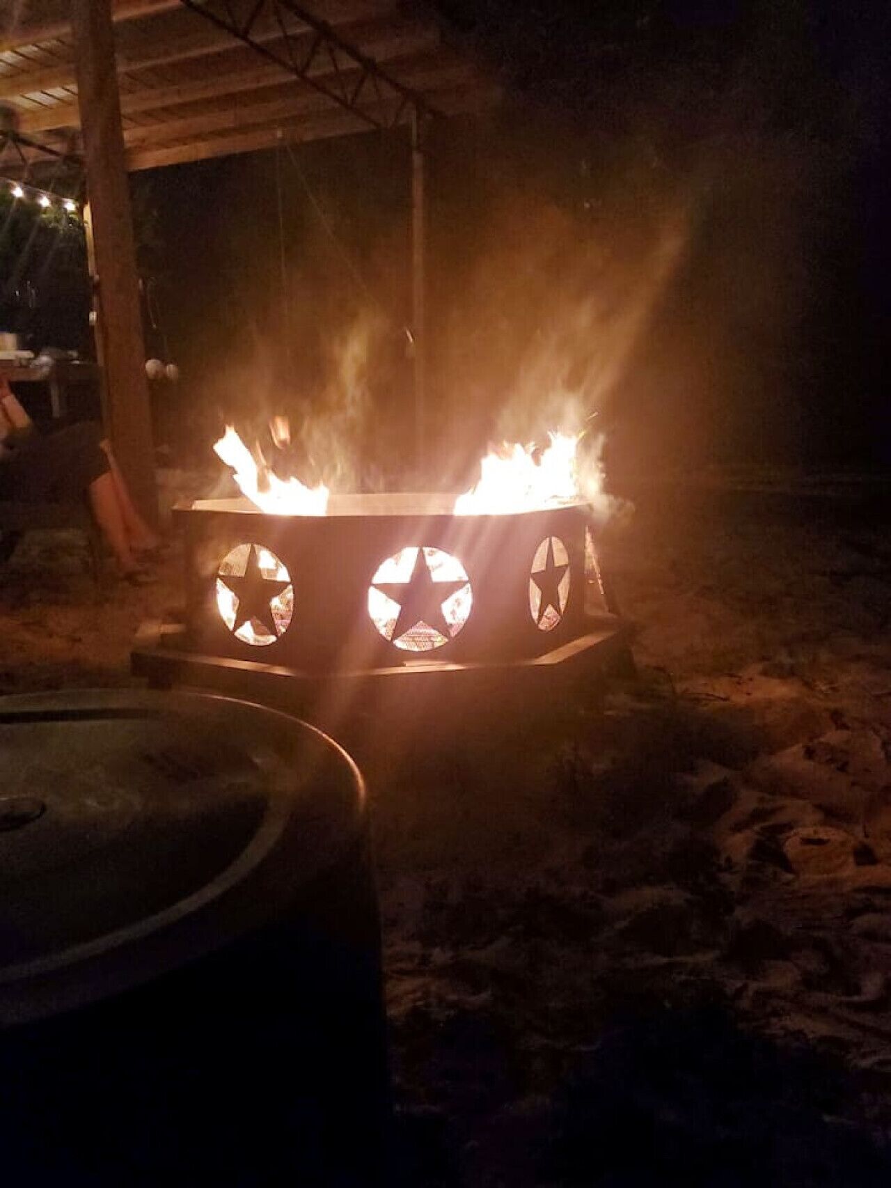 Ein Lagerfeuer mit einer Metallkonstruktion und sternförmigen Ausschnitten.