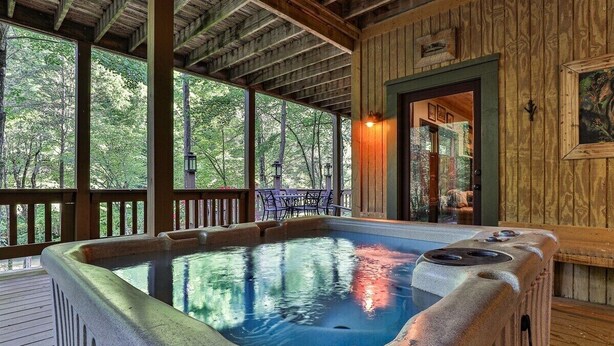 Een hottub op een houten terras, met uitzicht op bomen.