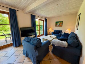 Un salon avec un téléviseur, deux canapés, une table basse et un tableau accroché au mur.