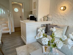 Una sala de estar con un sofá, una mesa de centro con un florero y una escalera, además de una puerta.