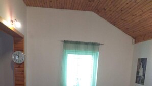A living room with a wooden ceiling, a sofa set, a coffee table, and a window with a curtain. - Remarkable 3-Bed House in Zabljak (Zabljak)