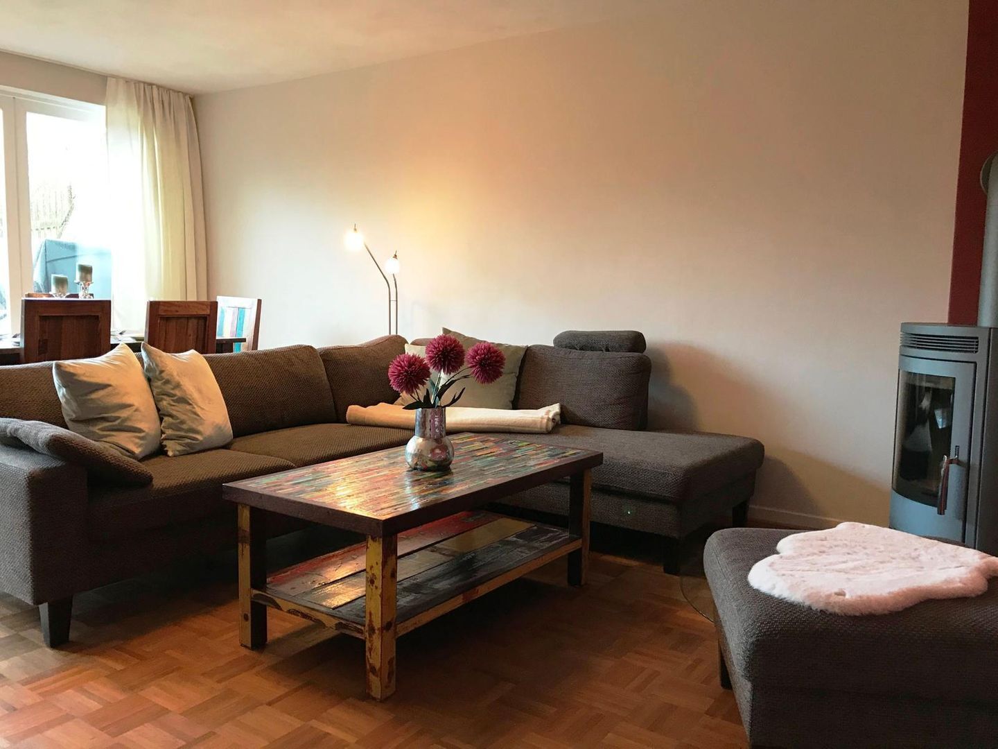 Una sala de estar acogedora con un sofá marrón, una mesa de centro de madera y un tapete rosa.