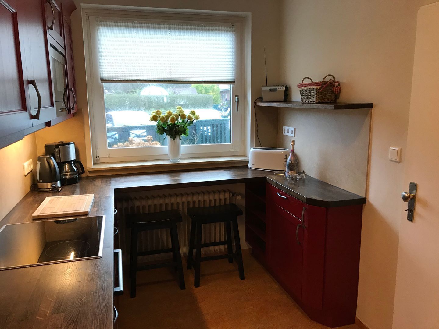 Una cocina compacta con ventana, cafetera, tostadora y una botella sobre la encimera.