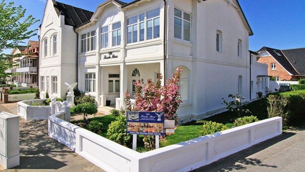 A large, white, two-story building with a prominent entrance and a sign indicating it is a hotel. - 2nd Seahorse, 70sqm for up to 2-3 persons - Villa Frische Brise (Sylt)