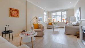 A spacious living room with a sofa, armchairs, a coffee table, and a dining table set for a meal. - 2nd Seahorse, 70sqm for up to 2-3 persons - Villa Frische Brise (Sylt)