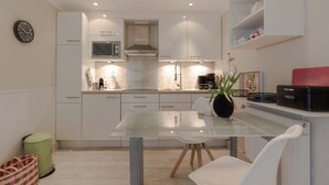 A modern kitchen with white cabinets, a glass dining table, and a microwave. - 2nd Seahorse, 70sqm for up to 2-3 persons - Villa Frische Brise (Sylt)
