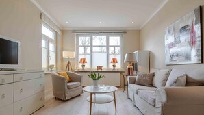 A living room with a TV, two sofas, a coffee table, and a painting on the wall. - 2nd Seahorse, 70sqm for up to 2-3 persons - Villa Frische Brise (Sylt)
