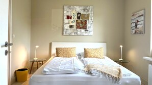 Un dormitorio con una cama, dos mesitas de noche, una obra de arte en la pared y un cuadro.