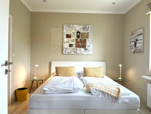 Una camera da letto con un letto, due comodini, un'opera d'arte a parete e un quadro.
