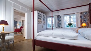 A four-poster bed with white linens, a red frame, and a bedside table with a lamp.