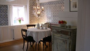 A dining room with a round table, chairs, a chandelier, and a vintage cabinet. - 2. Studio apartment, 65 square meters, 2 bedrooms, sleeps up to 4 people - Weidemannhaus (Sylt-Ost)