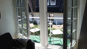 A room with a large sliding glass door leading to an outdoor patio with a table and chairs. - Wadden runner, 40sqm for up to 2 people - Haus am Wattenmeer (Sylt)