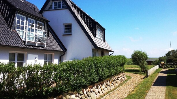 A two-story house with a steeply pitched roof and white exterior walls. - Wadden runner, 40sqm for up to 2 people - Haus am Wattenmeer (Sylt)