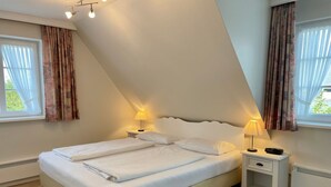 A bedroom with a bed, two bedside tables, and a nightstand.