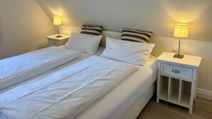 Une chambre double avec deux lits, des tables de chevet avec des lampes et un petit placard.