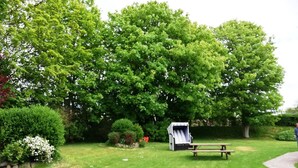 En plats för picknick med ett bord och bänkar, omgiven av frodig grönska och träd.