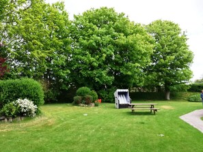 A picnic area with a table and benches, surrounded by lush greenery and trees. - Appartement West, 45qm für bis zu 2 Personen - Altes Friesenhaus (Sylt-Ost)