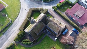 Vue aérienne d’un bâtiment à la façade en pierre, entouré de pelouses bien entretenues et d’un espace de stationnement.