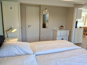 Un dormitorio con cama, mesita de noche, lámpara, armario y cómoda pequeña.