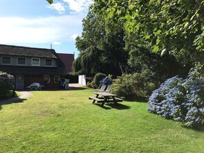 A house with a thatched roof, a lawn, and a picnic table. - Apartment East, 55sqm for up to 3 persons - Altes Friesenhaus (Sylt-Ost)