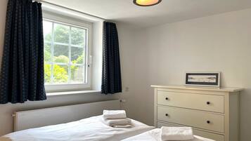 A bedroom with a bed, a nightstand, a window with curtains, and a ceiling light.