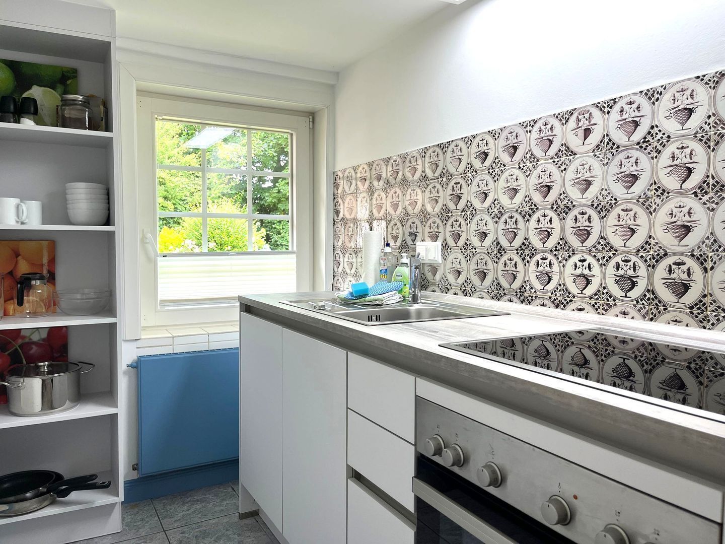 A kitchen with white cabinets, a window, and a patterned backsplash.