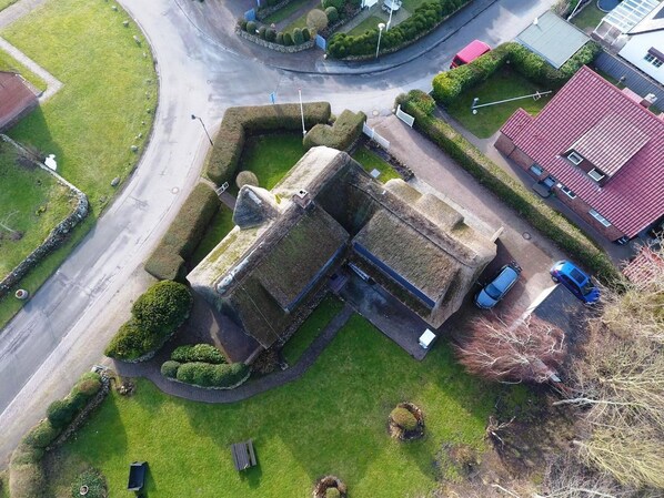 An aerial view of a building with a stone facade, surrounded by well-maintained lawns and a parking area.