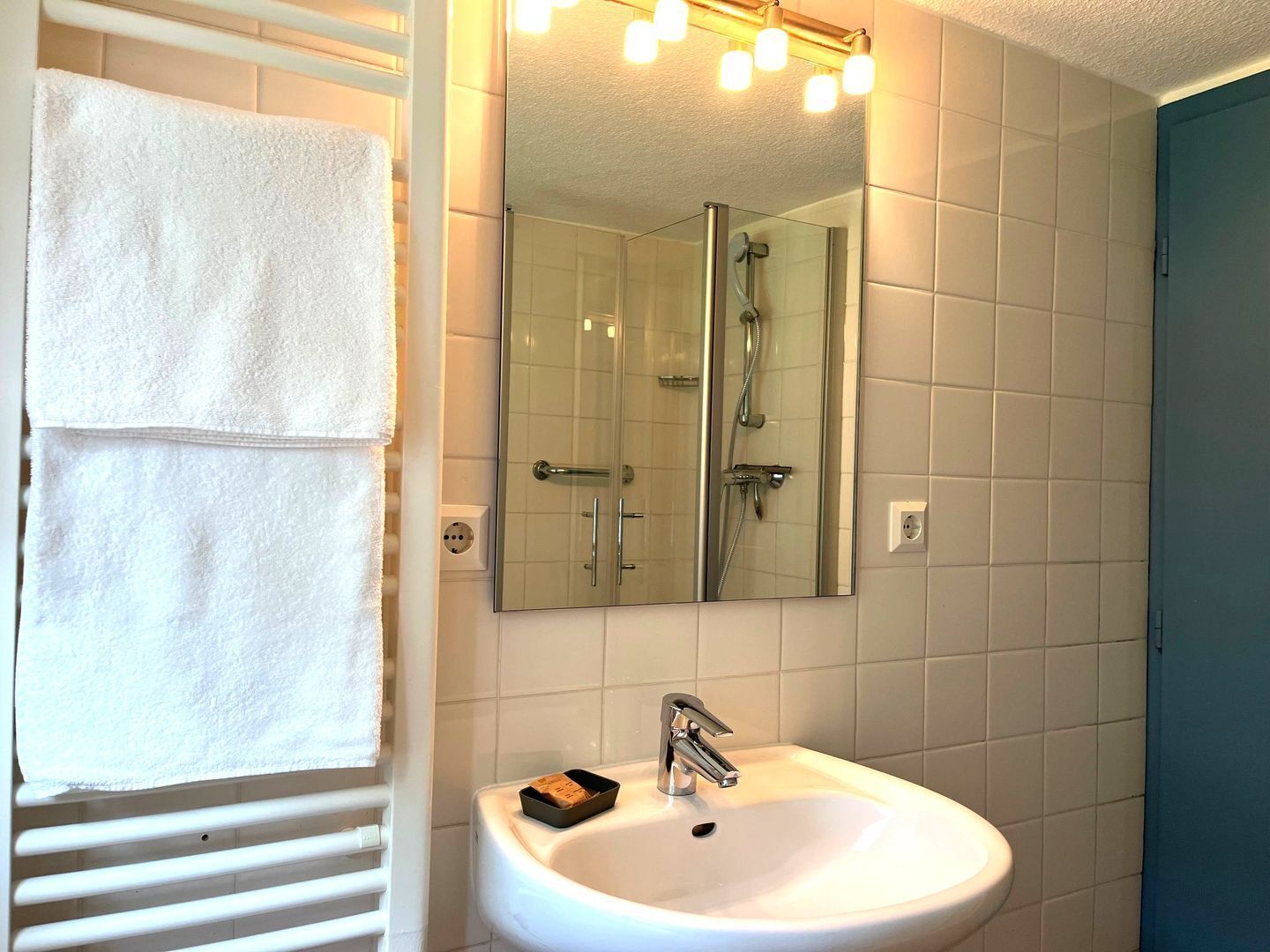 A bathroom with a white sink, a mirror, and a shower enclosure.