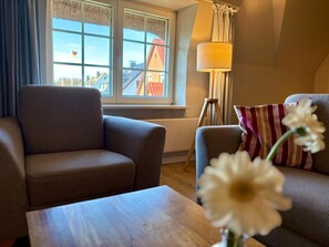A living room with a sofa, a table, and a lamp. - Unterm Reet, 100qm für bis zu 5 Personen - Altes Friesenhaus (Sylt-Ost)