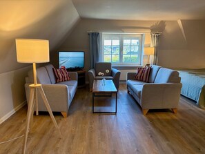 A cozy living room with two sofas, a coffee table, a TV, and a lamp. - Unterm Reet, 100qm für bis zu 5 Personen - Altes Friesenhaus (Sylt-Ost)