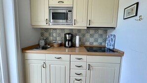 A compact kitchen with a microwave, a coffee maker, and a sink. - First floor, 50sqm for up to 2 persons - Haus Thomsen (Sylt)