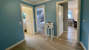 Een kamer met een houten vloer, een witte deur en een klein tafeltje met een schaal.