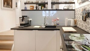 Een moderne keuken met een zwart aanrecht, roestvrijstalen apparatuur en een spatwand met een bloemmotief.
