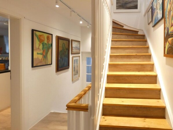 A staircase with wooden steps and a white railing, leading to an upper floor.