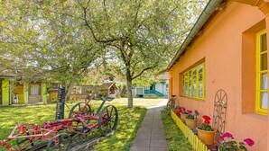 Un jardin avec un sentier, un vélo et un charrue rouge.