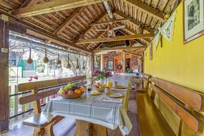 Un coin repas en bois, avec une table dressée pour le petit-déjeuner, des bancs et des luminaires suspendus.