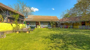 Une maison traditionnelle en bois, avec un toit de chaume, une pelouse bien entretenue et une clôture en bois.