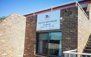 A building with a sign indicating 'BRUCES WATERSIDE Lookout Units: 10 - 11 - 12' and a contact number.