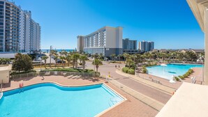 A resort with multiple swimming pools, a parking area, and high-rise buildings in the background. - Ariel Dunes I 303 * Last minute savings. Walk to Beach! Salt Water Vacations (Destin)