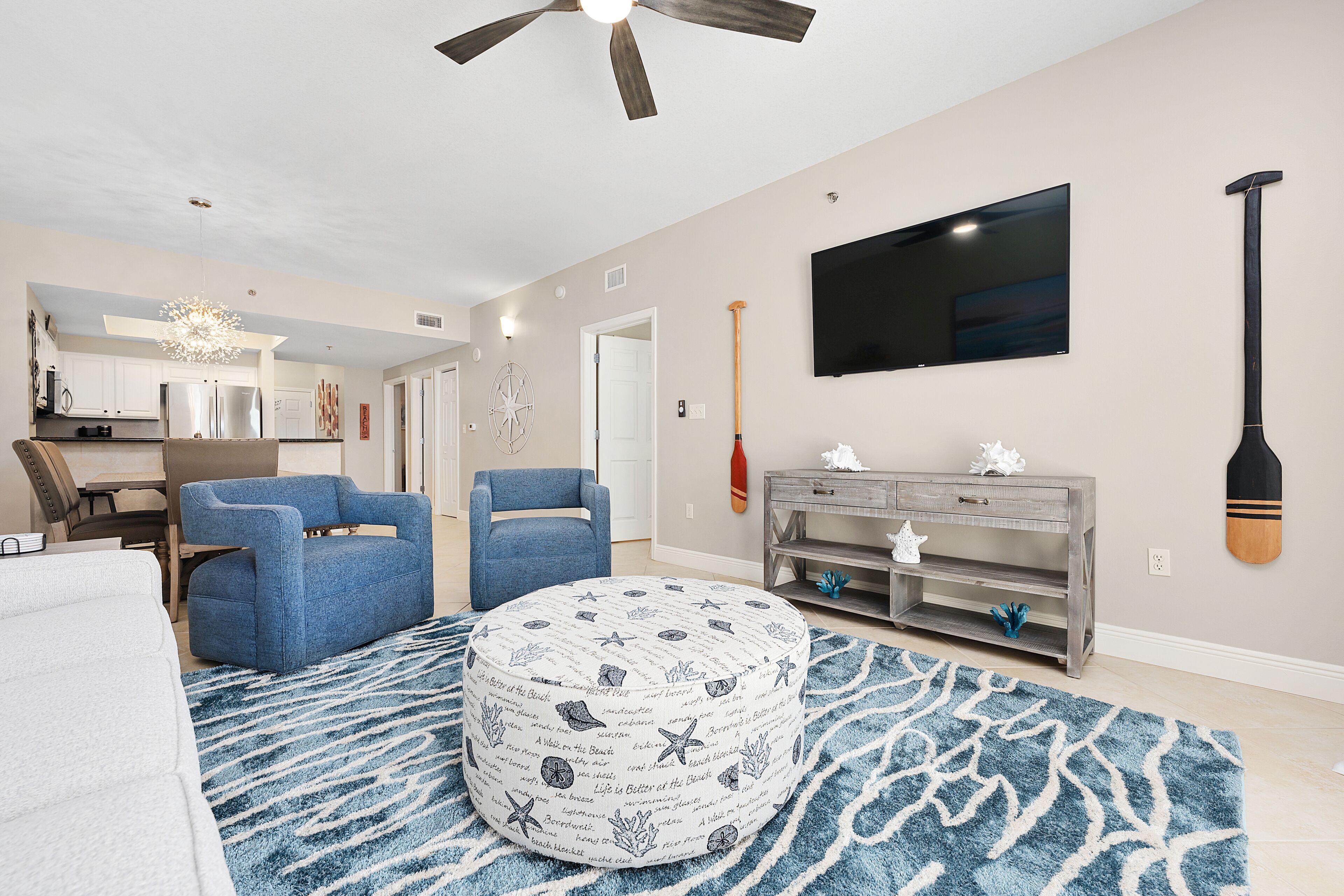 A modern living room with a round ottoman, a blue sofa, and a grey console table.