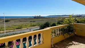 Un balcó amb vista al mar, un tren i un paisatge urbà a la distància.