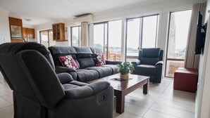 Een moderne woonkamer met een bank, fauteuils en een salontafel.